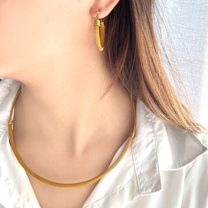 Detail of gold-tone jewelry set showing woven texture on necklace and earrings