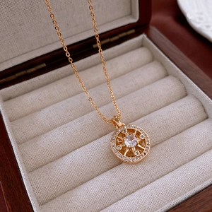 Macro view of a gold-plated circular pendant with clear zircon and starburst details