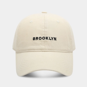 Detailed close-up of Brooklyn letter embroidery on off-white cotton baseball cap