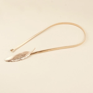 Close-up of golden leaf buckle on metallic spring waist belt for dresses and coats