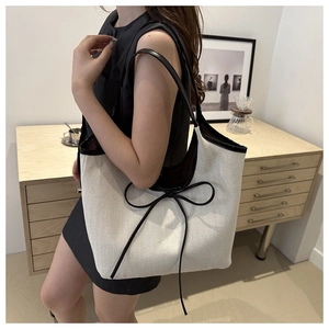 Detail view of large tote bag with herringbone texture and black ribbon bow accent