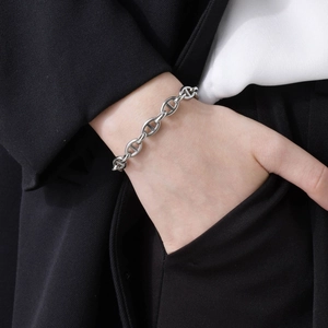 Close-up of a polished silver anchor link bracelet worn on a wrist with a formal suit