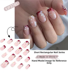 Detail of short square press-on nails with burgundy French tips and white flower designs