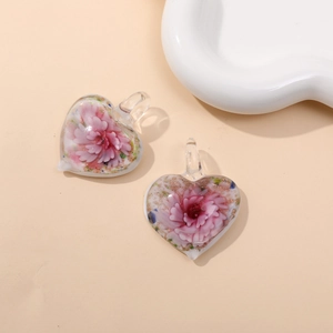 Macro view of heart-shaped glass pendant featuring internal pink flower patterns