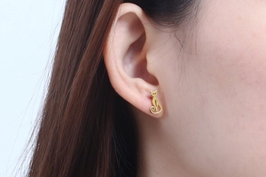 Close-up of a minimalist golden cat-shaped stud earring worn by a model