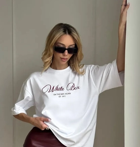 Λεπτομέρεια λευκό βαμβακερό T-shirt με vintage γράμματα και κόκκινη δερμάτινη φούστα