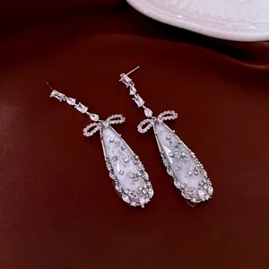 Elegant silver bow drop earrings with sparkling crystals and water-drop pendants on silk