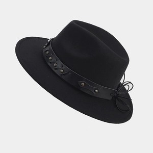 Detalle de sombrero fedora negro con banda de cuero, tachuelas de metal vintage y un lazo