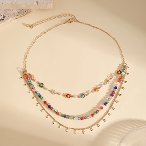 Detailed close-up of layered necklace with colorful floral beads and metal waterdrop pendant