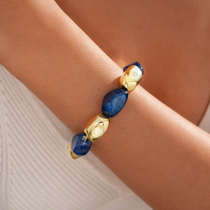 Detail of bohemian acrylic oval beads and golden metal spheres on a women's bracelet