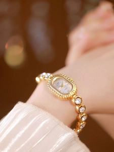 Close-up of a vintage oval gold watch with crystal-encrusted bracelet on a wrist