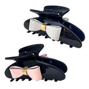 Detailed view of elegant black resin hair claws with white and pink bow accents