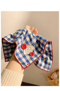 Detail of blue plaid fabric hair scrunchie with cherry embroidery and handmade label
