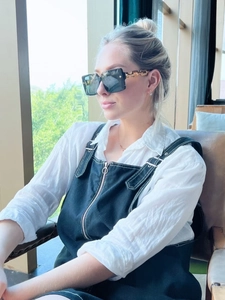 Close-up of square sunglasses featuring golden hollow chain design on the black temples