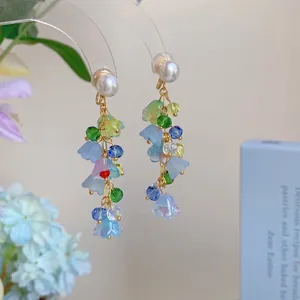 Détail de boucles d'oreilles bohèmes avec fleurs en résine pastel et glands en cristal