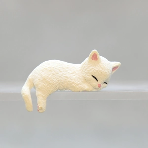 Close-up of a white sleeping cat ornament with realistic fur texture on a grey background