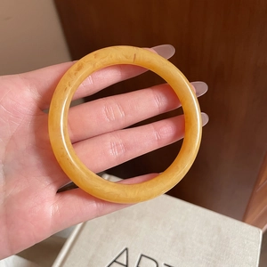 Detailed close-up of amber resin bangle with marble texture held in hand