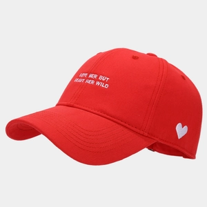 Detail of red cotton baseball cap with white side heart embroidery and cursive text