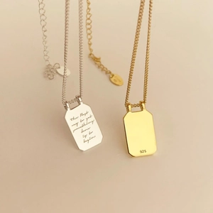 Macro detail of 925 sterling silver tag necklaces with inspirational quotes in gold and silver