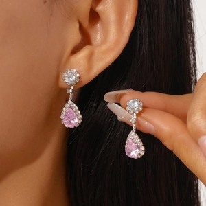 Macro shot of silver drop earrings with pink pear-cut zircon and shimmering halo stones