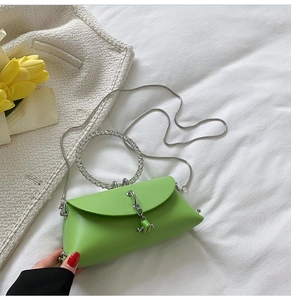 Close-up of green mini evening bag with rhinestone handle and silver chain on white linen