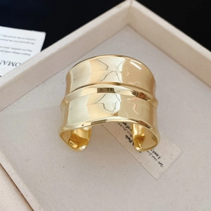 Vue détaillée d'un bracelet manchette doré géométrique large sur un plateau en velours
