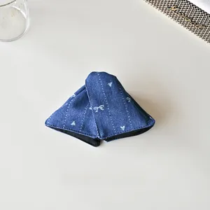Détail d'une pince à cheveux triangulaire en denim avec nœuds blancs et pois rétro