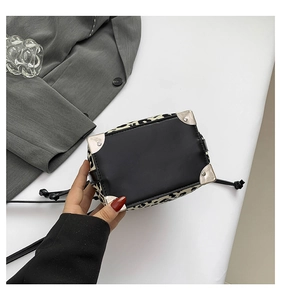 Detailed close-up of leopard print bucket bag with silver metal corners and leather base