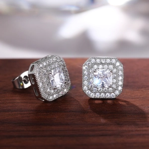 Macro detail of silver square halo stud earrings with cubic zirconia on a wooden stand