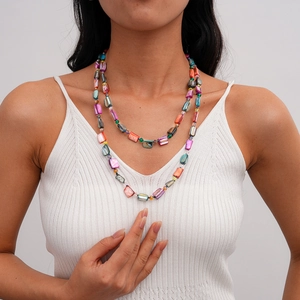 Detail of bohemian layered necklace with colorful rectangular shell beads on a model