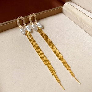 Detailed view of elegant gold bow earrings with zircon rings and long snake chain tassels