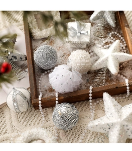 Close-up of white and silver glitter Christmas ornaments on a rustic wooden tray with pine