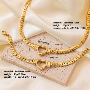 Golden titanium steel Cuban chain jewelry set with hollow heart pendants on beige silk background