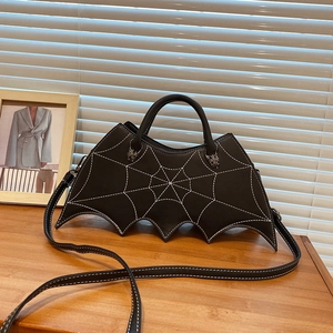Detail of bat-wing shaped PU leather handbag featuring white spiderweb embroidery and metal hardware