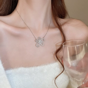 Detail of a sparkling silver flower pendant necklace with diamonds worn by a model