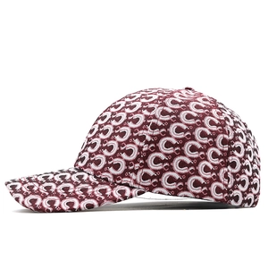Detail of burgundy baseball cap with jacquard texture and repeating C-pattern embroidery