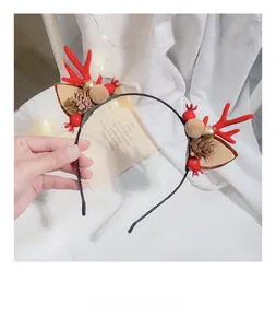 Detail showing red reindeer antlers with pine cones and berries on a festive headband