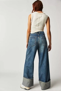 Macro detail of the wide folded cuffs and high-quality washed blue denim texture