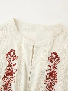 Detailed macro view of red floral embroidery and lace trim on linen women top