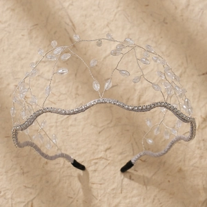 Detail of silver bridal headband with crystal beads and rhinestones on beige background