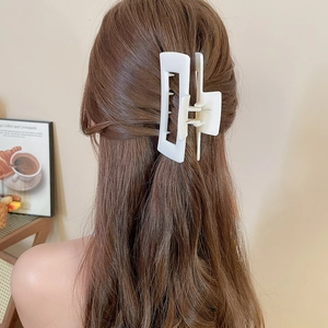 Close-up of matte white rectangular hollow hair claw clip holding long hair in a bun