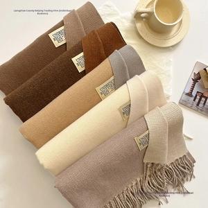 Detail showing various earth-toned double-sided cashmere scarves with delicate fringe edges