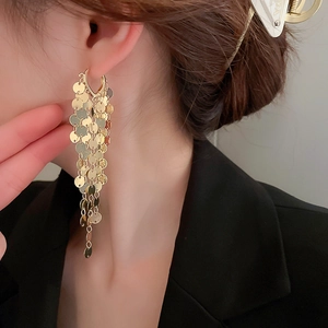 Detailed close-up of long gold layered sequin tassel earrings on a fashion model