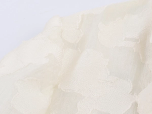 Gros plan sur un tissu en dentelle blanche avec broderie fine et texture soyeuse