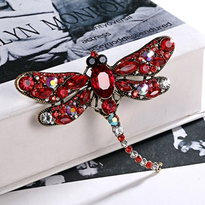Vintage dragonfly brooch with red rhinestones and antique gold finish on art book