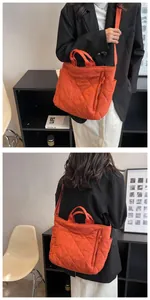 Detail view of large quilted puffer tote bag in orange featuring padded diamond texture