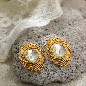 Detail of vintage 18K gold plated spiral earrings with clear crystal on natural rock