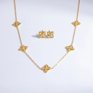 Detail shot of four-leaf clover bracelet and earrings set with clear crystals and 18k gold finish