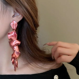 Close-up of long rose pink pleated petal tassel earrings worn by a model