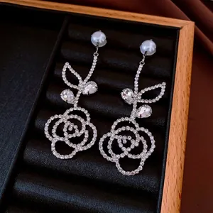 Elegant silver rose drop earrings with pearls and crystals on a black jewelry tray